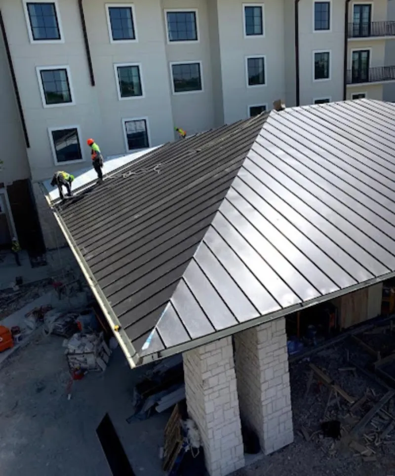 Crew installing standing seam metal roof panels on a commercial project in Blackfoot